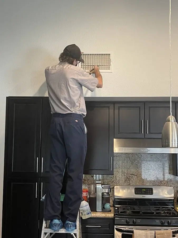 Technician inspecting an air vent during HVAC service in Uvalde
